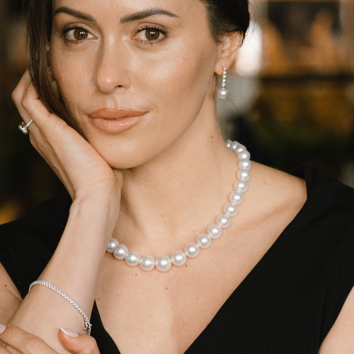 Single strand of South Sea pearls worn at the neckline with a black dress.