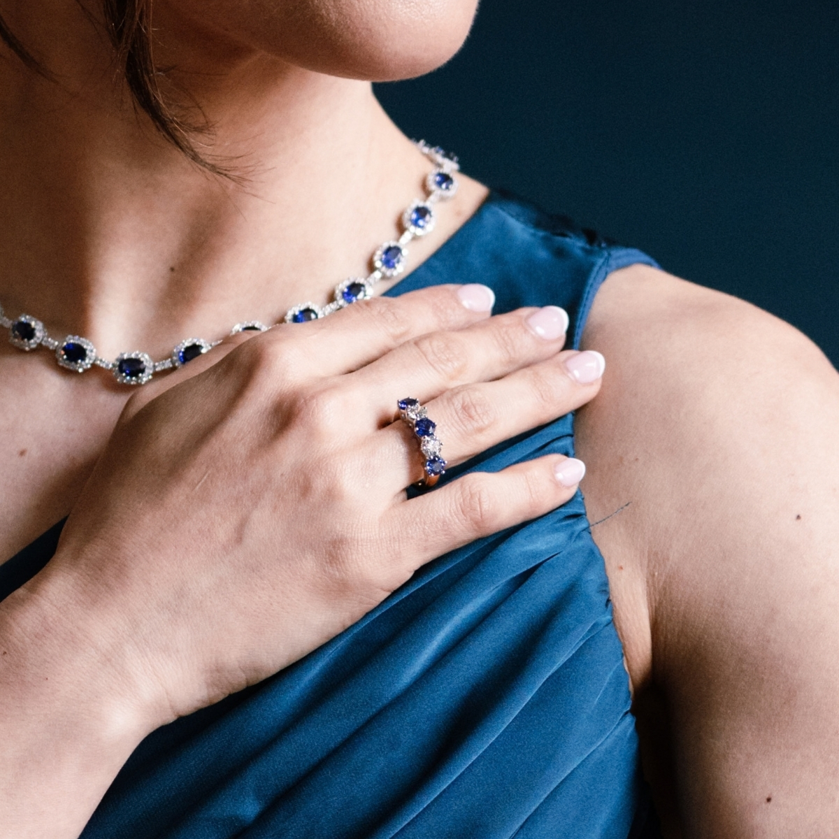 Yellow gold sapphire and diamond eternity ring, worn on the hand with a sapphire necklet.