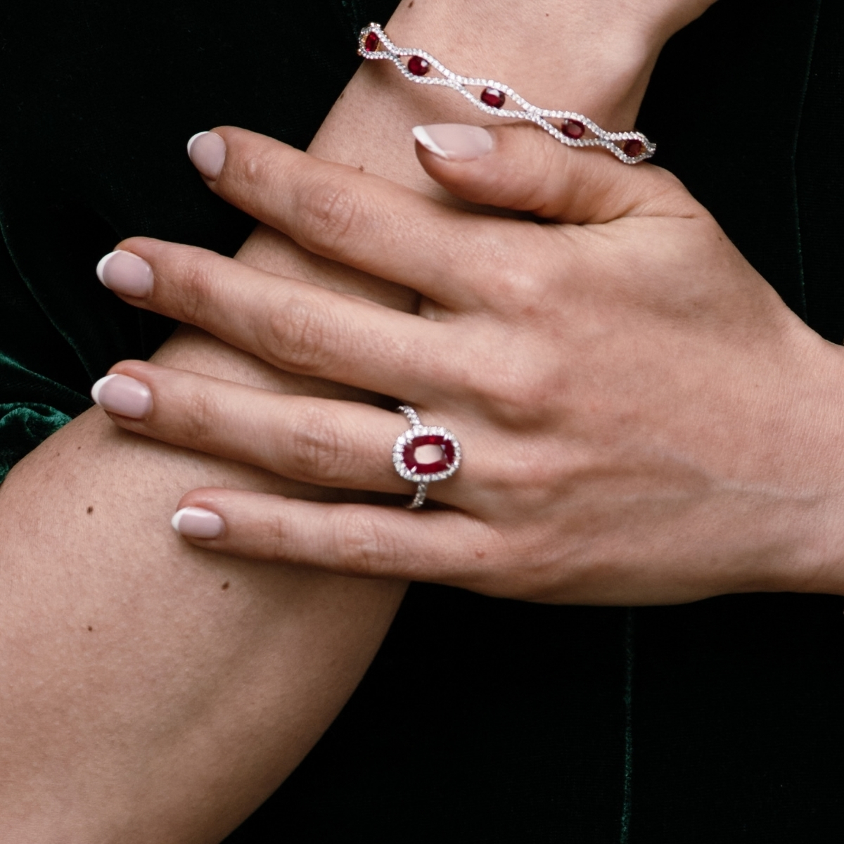 Platinum oval ruby and diamond cluster ring with a diamond halo and diamond-set band, worn on the hand.