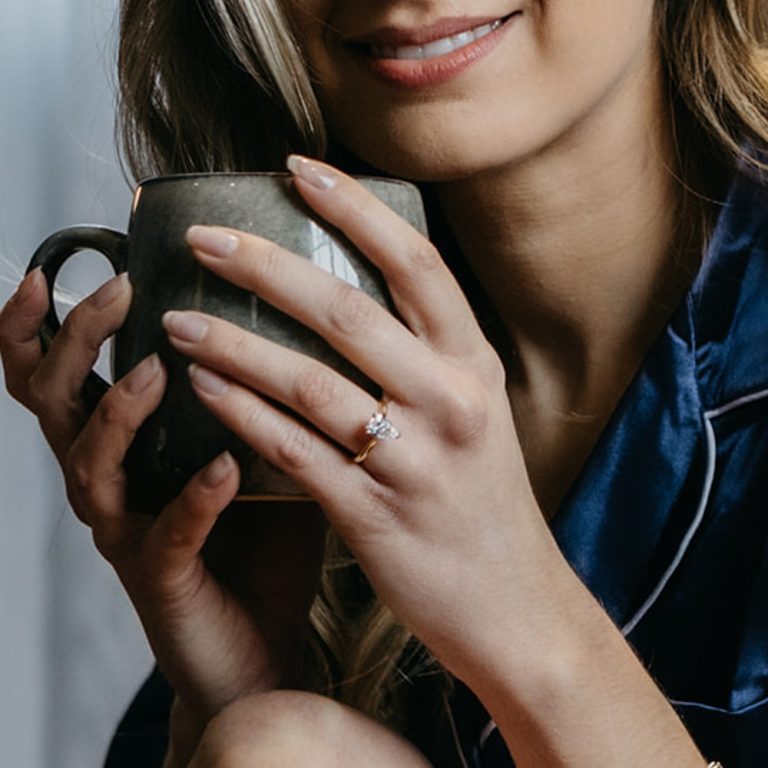 ladies hand wearing a diamond ring holding a coffee cup