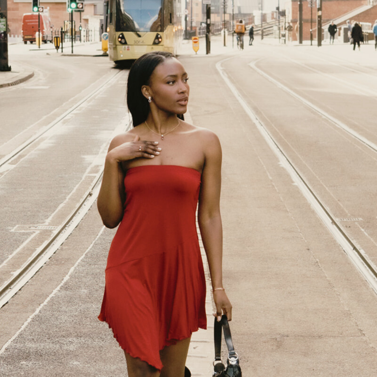 lady in red dress walking down centre of a road