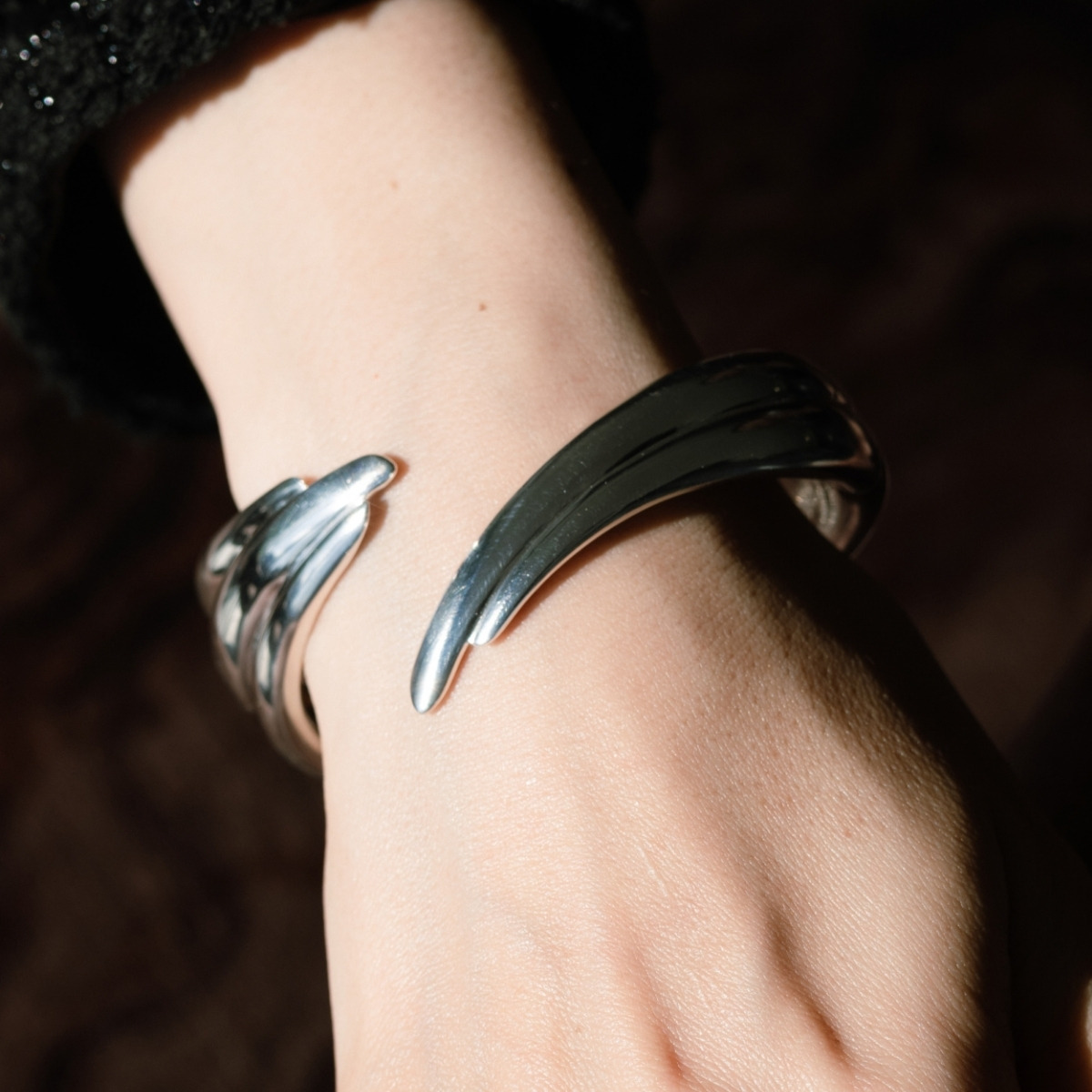 Georg Jensen Arc bangle in sterling silver, an open design with sculpted ends, worn on the wrist.