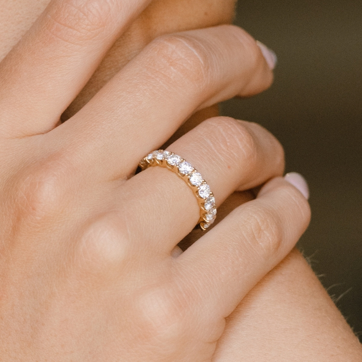 Yellow gold diamond eternity ring set with ten brilliant cut diamonds, worn on the finger.