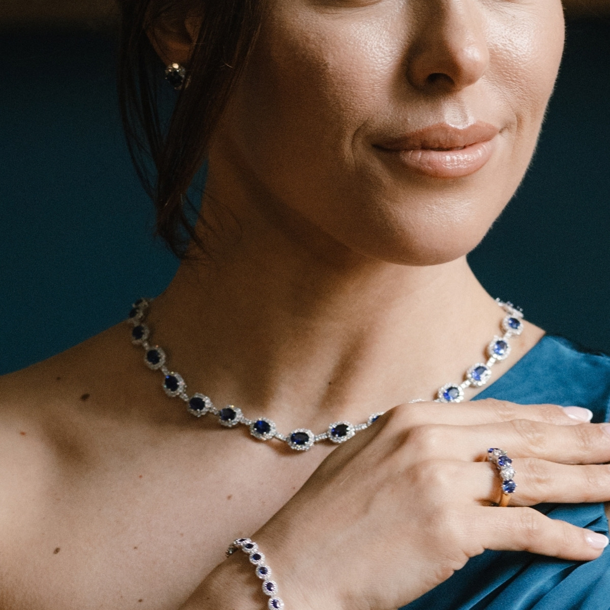 18ct white gold sapphire and diamond necklet with oval halo-set sapphires, worn at the neckline.