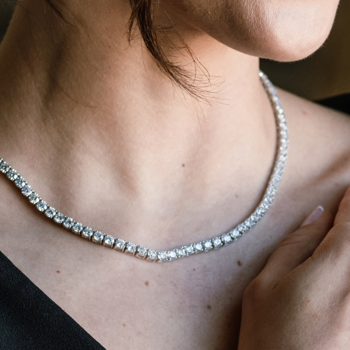4-claw brilliant cut diamond line necklace, worn at the neckline with a black dress.