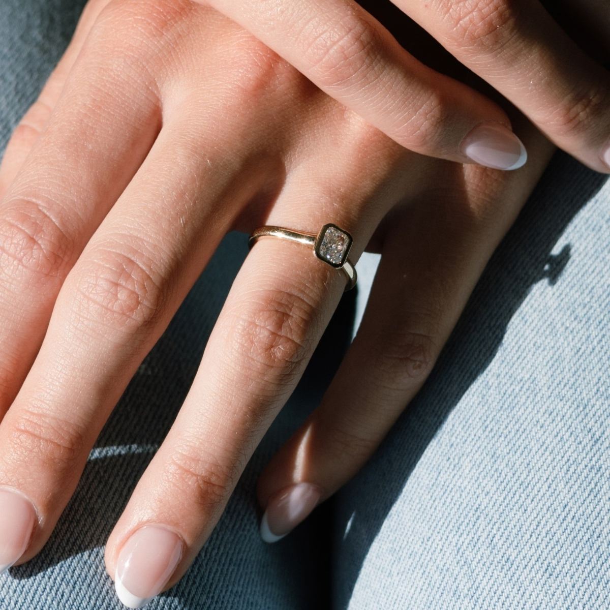 Radiant cut diamond ring rubbed over in yellow gold, worn on the hand.