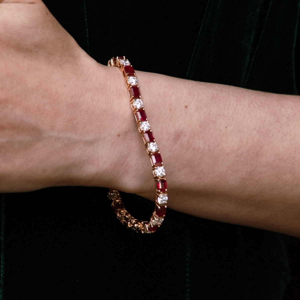 Yellow gold ruby and diamond line bracelet with alternating rubies and diamonds, worn on the wrist.