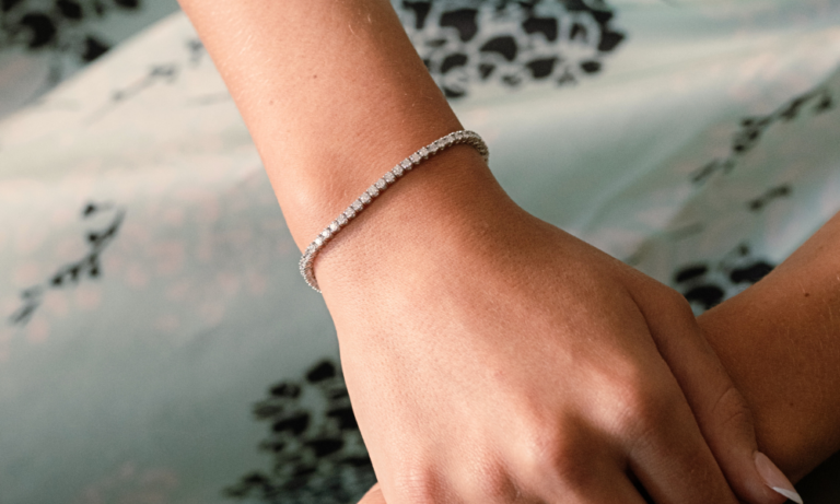Woman's hand placed over her other hand with a tennis bracelet on in summer weather.