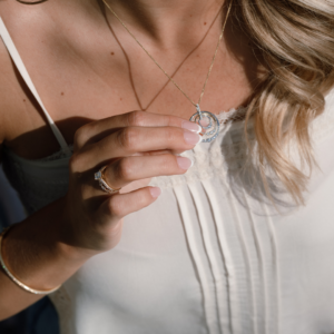 Woman holiday a diamond pendant with a diamond ring on her finger in the sunshine. close up
