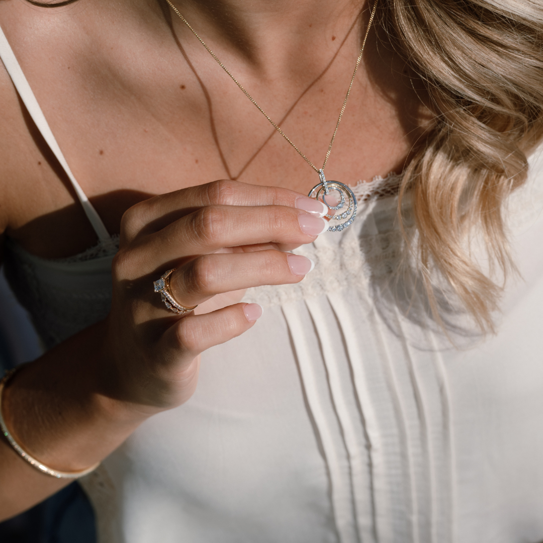 Woman holiday a diamond pendant with a diamond ring on her finger in the sunshine. close up