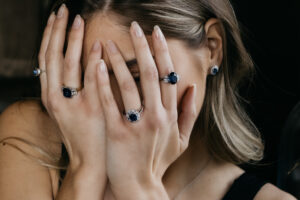 A woman wearing solitaire rings and three-stone rings, which are sapphire